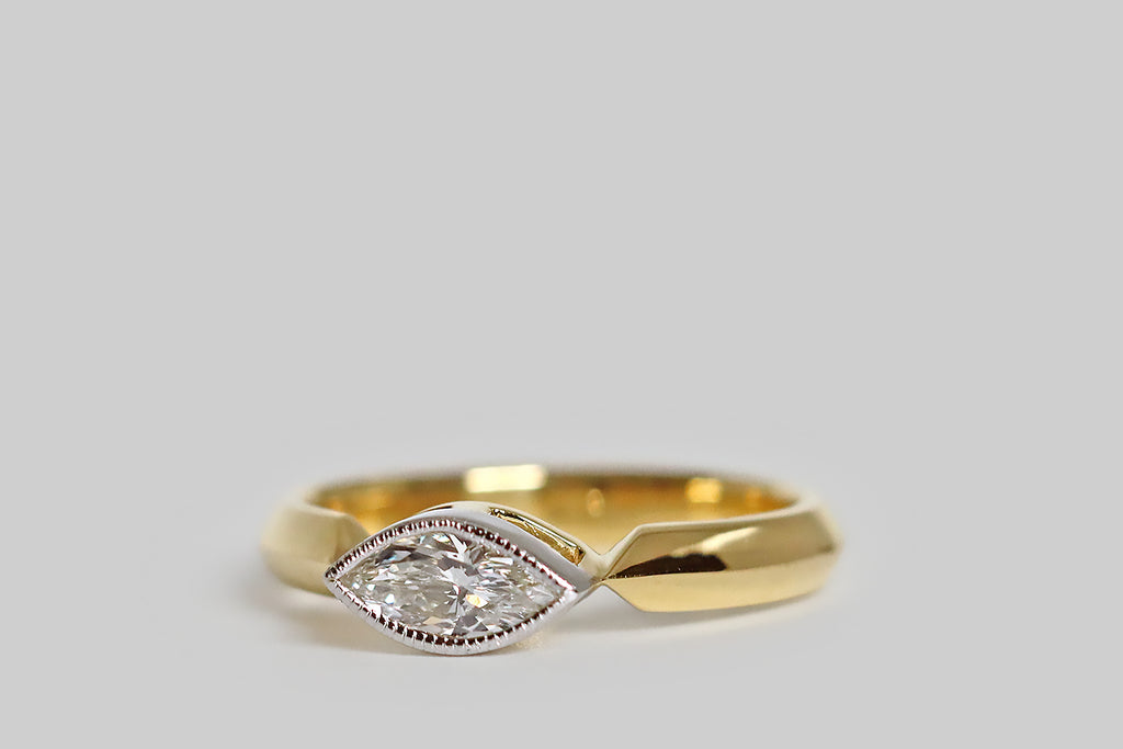 Poor Mouchette | Curated Antique Jewelry, Vintage Jewelry & Engagement Rings | Portland, Oregon | An elegant, low-profile engagement ring, modeled in 18k yellow gold and platinum, whose gem is an east/west oriented, vintage, marquise-cut diamond (.61 carats, G/H, VS). Our sparkling, eye-like diamond is set in a platinum bezel. This bezel is finished with a fine, milgrained edge, and it rests between the the shapely end-points of the ring's crisp cathedral shoulders. 
