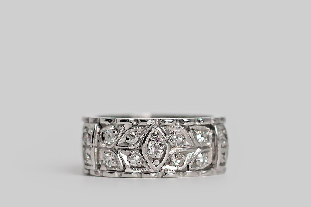 Poor Mouchette | Curated Antique Jewelry, Vintage Jewelry & Engagement Rings | Portland, Oregon | An elegant, wide, mid-20th-century, diamond-set eternity band, modeled in platinum, whose face is decorated with a balanced series of nested folate forms, interrupted, periodically by raised navette and strap-like forms. These many hand-pierced shapes are bead-set with old mine cut and single cut diamonds.