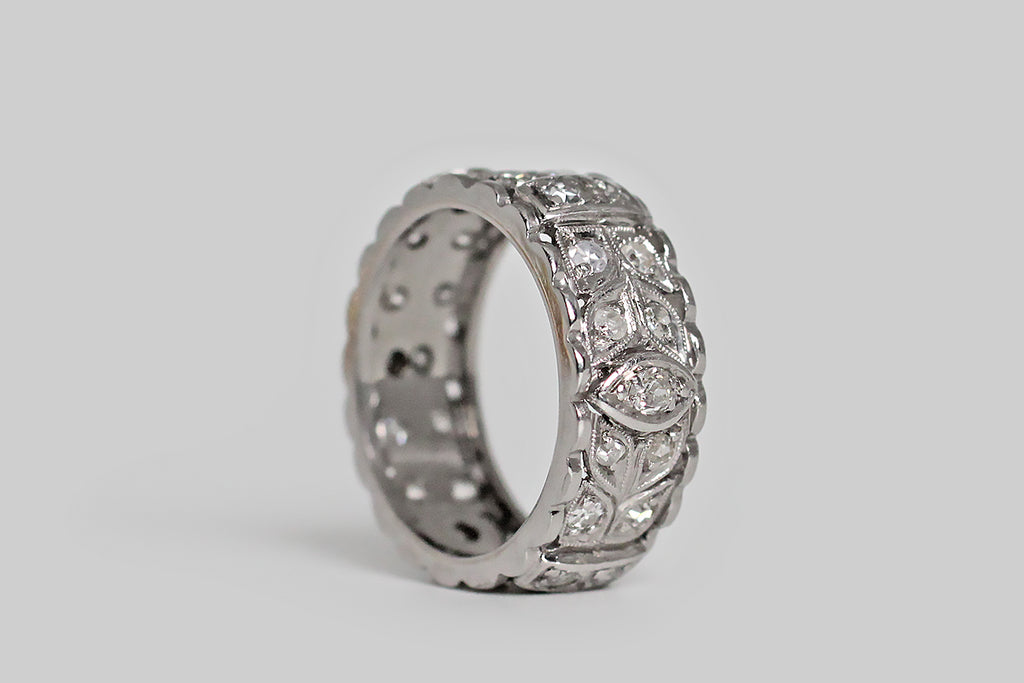 Poor Mouchette | Curated Antique Jewelry, Vintage Jewelry & Engagement Rings | Portland, Oregon | An elegant, wide, mid-20th-century, diamond-set eternity band, modeled in platinum, whose face is decorated with a balanced series of nested folate forms, interrupted, periodically by raised navette and strap-like forms. These many hand-pierced shapes are bead-set with old mine cut and single cut diamonds.