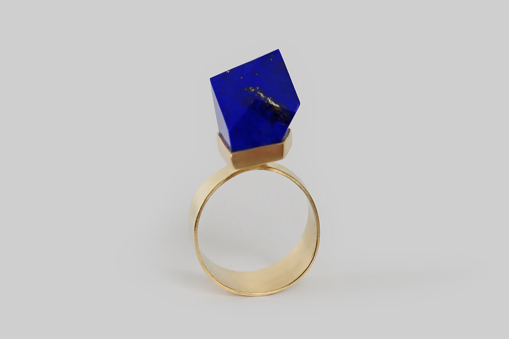 Antique Jewelry Portland, Vintage Jewelry Portland , Antique Engagement Rings | Poor Mouchette | A challenging modernist ring, created by Poor Mouchette, in 14k yellow gold. This ring features an especially vibrant lapis lazuli gem, that is figured with bright gold flecks and splashes of pyrite. This lapis gem is cut with many large, blocky, irregular facets— it is set in a precisely fabricated bezel that floats atop the ring's broad, flat shank. The ring shank is tapered, to widen at the base.