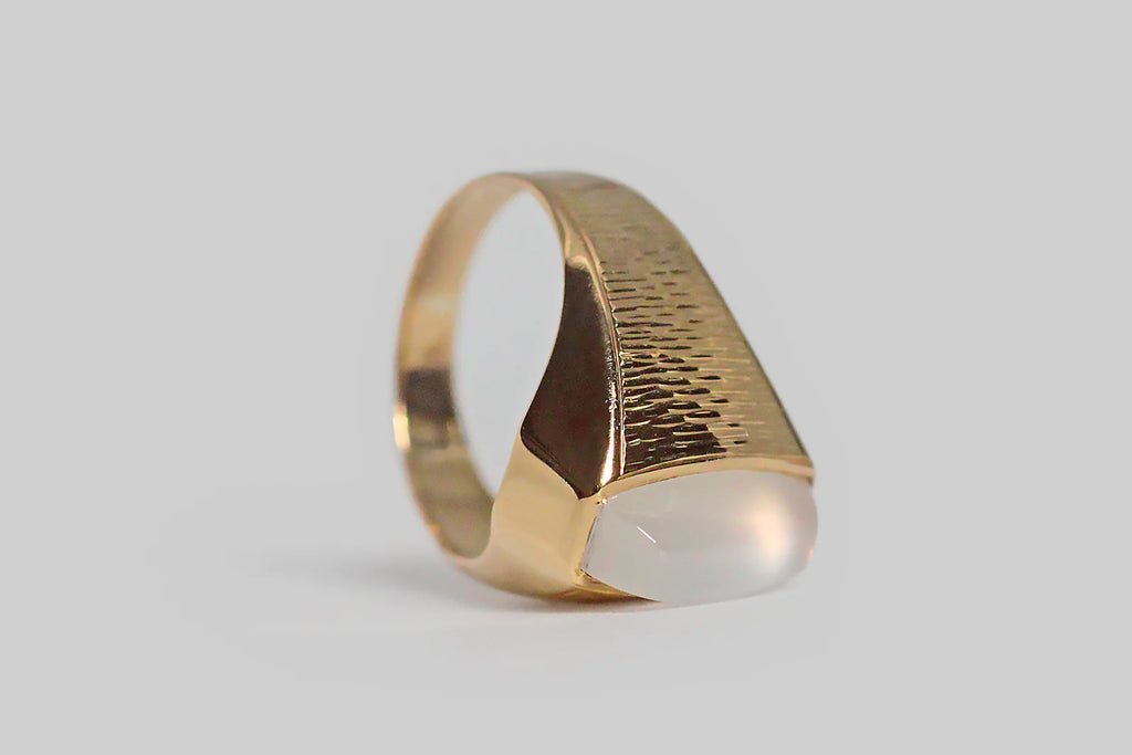 Poor Mouchette | Curated Antique Jewelry, Vintage Jewelry & Engagement Rings | Portland, Oregon | A striking vintage ring, modeled in 18k yellow gold, and set with a blue-flash moonstone of rare quality. This ring's modified sugarloaf moonstone is bezel set, and it really sings— the surface of its backside is completely covered by the iridescent play of blue and pink color that makes the best moonstones so breathtaking.