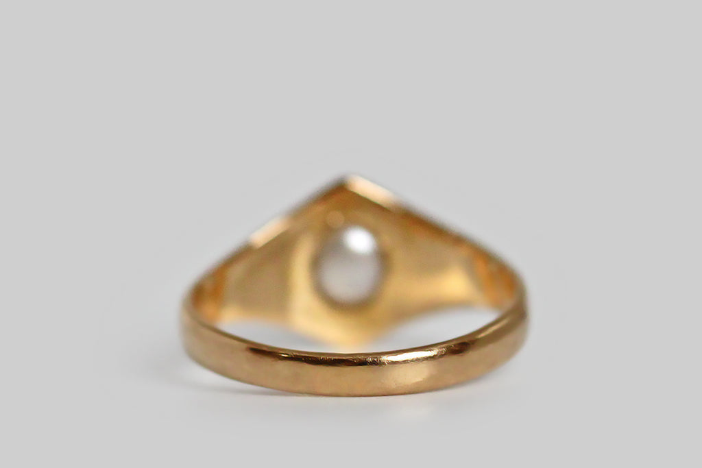 A shapely, mid-twentieth-century ring, modeled in 18k yellow gold and set with a luminous, white, button-shaped, saltwater pearl. This ring’s perfectly balanced form is two-peaked, with simple, deeply-carved shoulder details that are reminiscent of folded paper or fabric. This is simple, elegant, and mystical-seeming, bearing some resemblance to anthroposophical designs. T