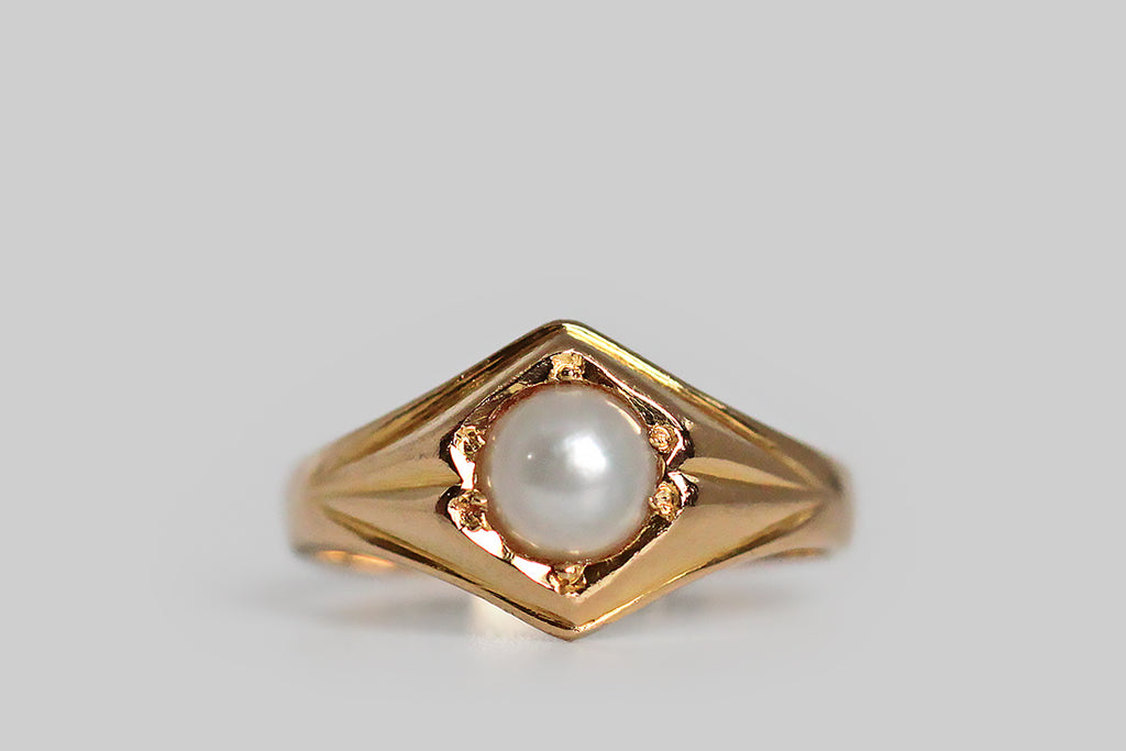 A shapely, mid-twentieth-century ring, modeled in 18k yellow gold and set with a luminous, white, button-shaped, saltwater pearl. This ring’s perfectly balanced form is two-peaked, with simple, deeply-carved shoulder details that are reminiscent of folded paper or fabric. This is simple, elegant, and mystical-seeming, bearing some resemblance to anthroposophical designs. T