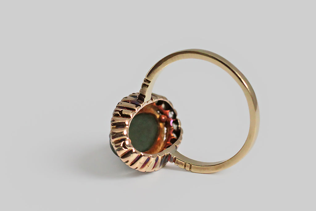 A Victorian-era ring, whose satiny, oval, nephrite jade cabochon is encircled by a halo of the loveliest old mine cut diamonds. These old darlings have the tall presence and tiny tables that give them their unique, soulful character; their exquisite sparkle, set against the soft, opaque nephrite is especially winning. The jade cabochon is set in a milgrain bezel. 