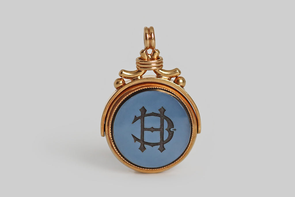 Antique Jewelry Portland, Vintage Jewelry Portland , Antique Engagement Rings | Poor Mouchette | A wonderful, large, Victorian-era fob, modeled in 15k yellow gold and set with an intaglio carved, layered (blue) agate gem. This fine, hand-carved, wax seal is two-sided; it features a unicorn's head on one side, and a monogram (HC) on the other. The unicorn is heroic— shown in profile atop a ribbon base, its beard and mane wave. Below our unicorn's head, a curling banner features the motto "over fork over,"