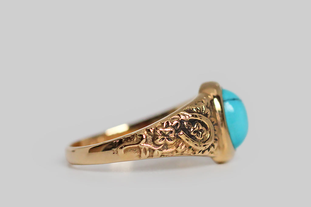 The Periapt ring, modeled 14k yellow gold, in the image of a beloved Victorian era jewel, and featuring a brilliant-blue, Sleeping Beauty turquoise cabochon. Our Periapt ring is so-called because its carved decor is a collection of lucky charms: a horseshoe, a wishbone, and a handful of four leaf clovers . . . a spattering of cheerful flowers flesh out the design. This ring is substantially made, with a classic tapering profile, and its turquoise gem is bezel set. It is ideal for frequent wear. 