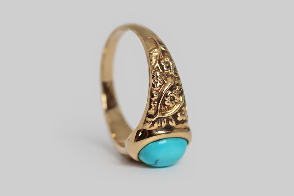 The Periapt ring, modeled 14k yellow gold, in the image of a beloved Victorian era jewel, and featuring a brilliant-blue, Sleeping Beauty turquoise cabochon. Our Periapt ring is so-called because its carved decor is a collection of lucky charms: a horseshoe, a wishbone, and a handful of four leaf clovers . . . a spattering of cheerful flowers flesh out the design. This ring is substantially made, with a classic tapering profile, and its turquoise gem is bezel set. It is ideal for frequent wear. 