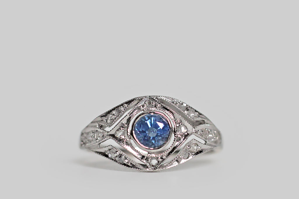 Poor Mouchette | Curated Antique Jewelry, Vintage Jewelry & Engagement Rings | Portland, Oregon | A delicate, Edwardian-era engagement ring, modeled in 18k yellow gold, with a platinum-foiled top, whose central gem is a natural, medium-blue, Ceylon sapphire (approx .40 carats). This ethereal old beauty features an intricate, diamond-studded, open-work face, replete with fine, milgrain details. The cool-blue sapphire is set in a floating bezel, and the ring's scattered, glinting, rose cut diamonds 