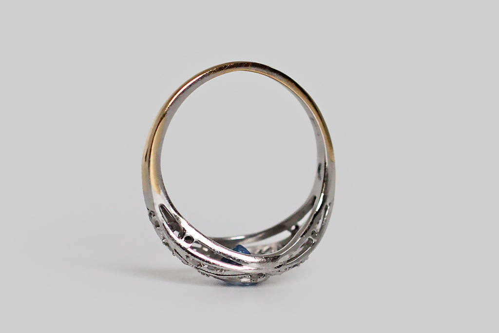 Poor Mouchette | Curated Antique Jewelry, Vintage Jewelry & Engagement Rings | Portland, Oregon | A delicate, Edwardian-era engagement ring, modeled in 18k yellow gold, with a platinum-foiled top, whose central gem is a natural, medium-blue, Ceylon sapphire (approx .40 carats). This ethereal old beauty features an intricate, diamond-studded, open-work face, replete with fine, milgrain details. The cool-blue sapphire is set in a floating bezel, and the ring's scattered, glinting, rose cut diamonds 