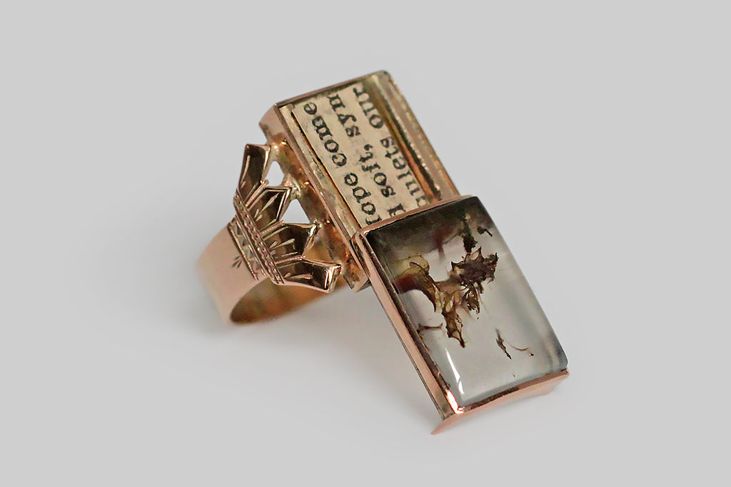 An unusual, Victorian-era, locket ring, with a sliding function, whose rectangular face is set with an outstanding plume agate cabochon. This translucent agate has highly-figural plume inclusions that read like a tender pair of tree or mushroom friends, leaning into one another on the floor of a tiny forest. The ring’s locket function is very discreet and is not noticeable when the face is closed. Its ornate, four-tine shoulders are deeply-engraved; its flat shank is weighty and broad.