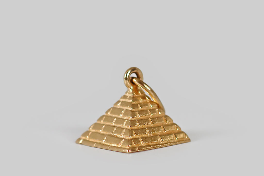 Poor Mouchette | Curated Antique Jewelry, Vintage Jewelry & Engagement Rings | Portland, Oregon | A very sweet miniature charm, modeled as an Egyptian pyramid, in 14k yellow gold. This pyramid is somewhat stylized, with a refined shape and individually carved, subtly-textured "bricks." It has a semi-polished finish, and it is matte in the recesses.
