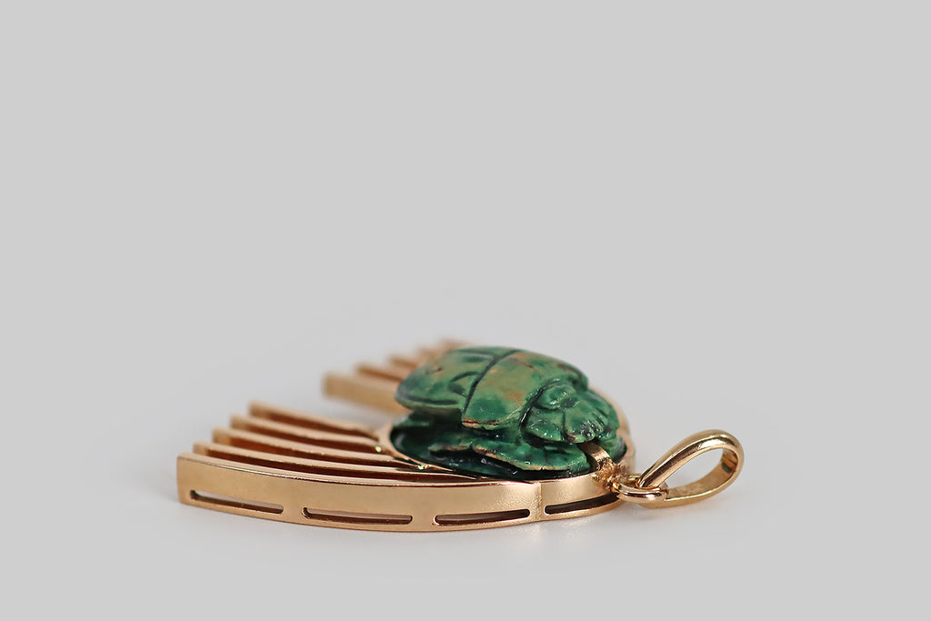 Antique Jewelry Portland, Vintage Jewelry Portland , Antique Engagement Rings | Poor Mouchette | A wonderful, unusual pendant, modeled in rosy 14k yellow gold, featuring a carved faience scarab, decorated with a blue-green glaze. This scarab beetle is set in a low profile bezel; series of heavy arched wires lay astride it, like wings. We love the upward movement implied by the wings here— we see them as swift, rainbow-like (even celestial, intergalactic), and truly cheerful!