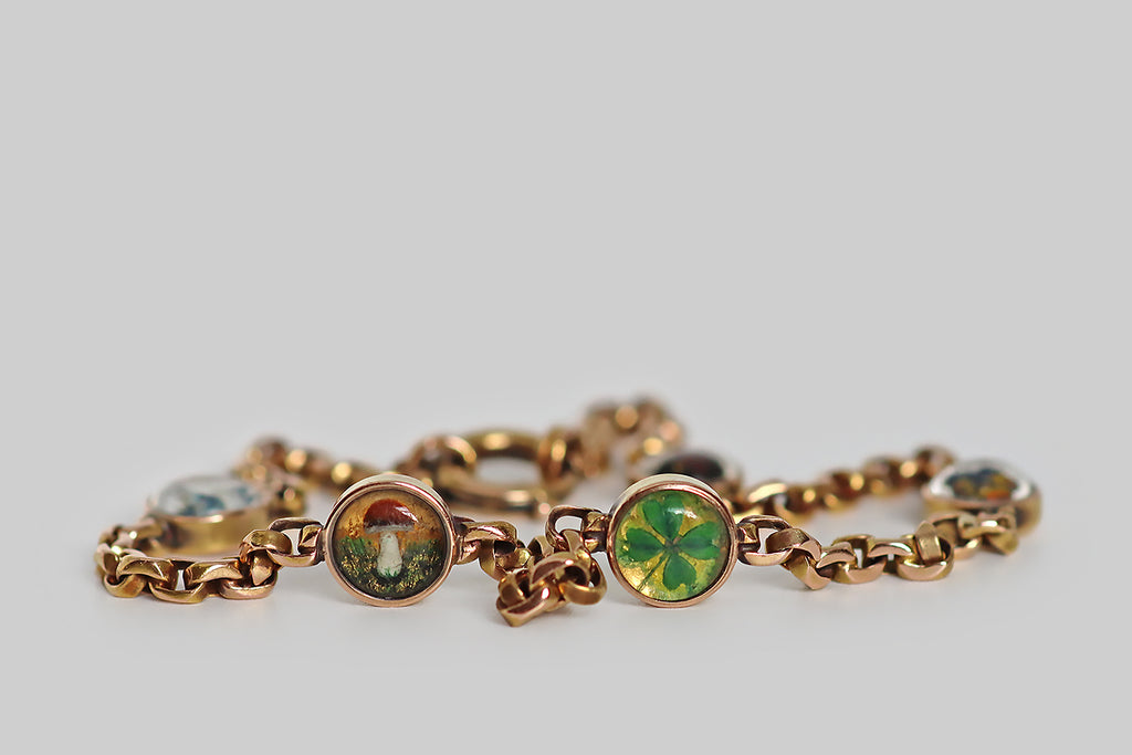 Poor Mouchette | Curated Antique Jewelry, Vintage Jewelry & Engagement Rings | Portland, Oregon | A rare and wonderful Victorian-era, cable-link bracelet, modeled in 14k rose gold, between whose stretches of faceted links miniature, reverse-painted crystals are stationed. These five, hand-painted Essex crystals are seriously dainty, and their highly-detailed, figural subjects are astonishing! Each hand-carved, hand-painted crystal is bezel set and features a lucky charm