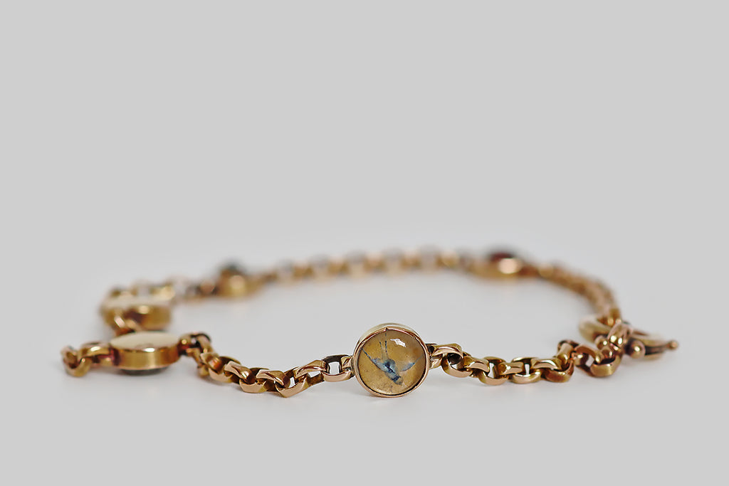Poor Mouchette | Curated Antique Jewelry, Vintage Jewelry & Engagement Rings | Portland, Oregon | A rare and wonderful Victorian-era, cable-link bracelet, modeled in 14k rose gold, between whose stretches of faceted links miniature, reverse-painted crystals are stationed. These five, hand-painted Essex crystals are seriously dainty, and their highly-detailed, figural subjects are astonishing! Each hand-carved, hand-painted crystal is bezel set and features a lucky charm