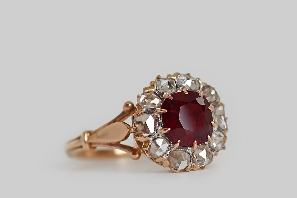 Poor Mouchette | Curated Antique Jewelry, Vintage Jewelry & Engagement Rings | Portland, Oregon | A striking, late-Victorian-era cluster ring, modeled in 18k rose gold, whose primary gemstone is a natural, untreated, 1.53 carat Burmese ruby. This vibrant, deep-red, cushion-shaped gem is held in ten claw-like prongs, where it is surrounded by a halo of ten glinting, rose cut diamonds. These soulful, hand-cut diamonds have domed faces with charming, irregular facets— they are flat-backed.