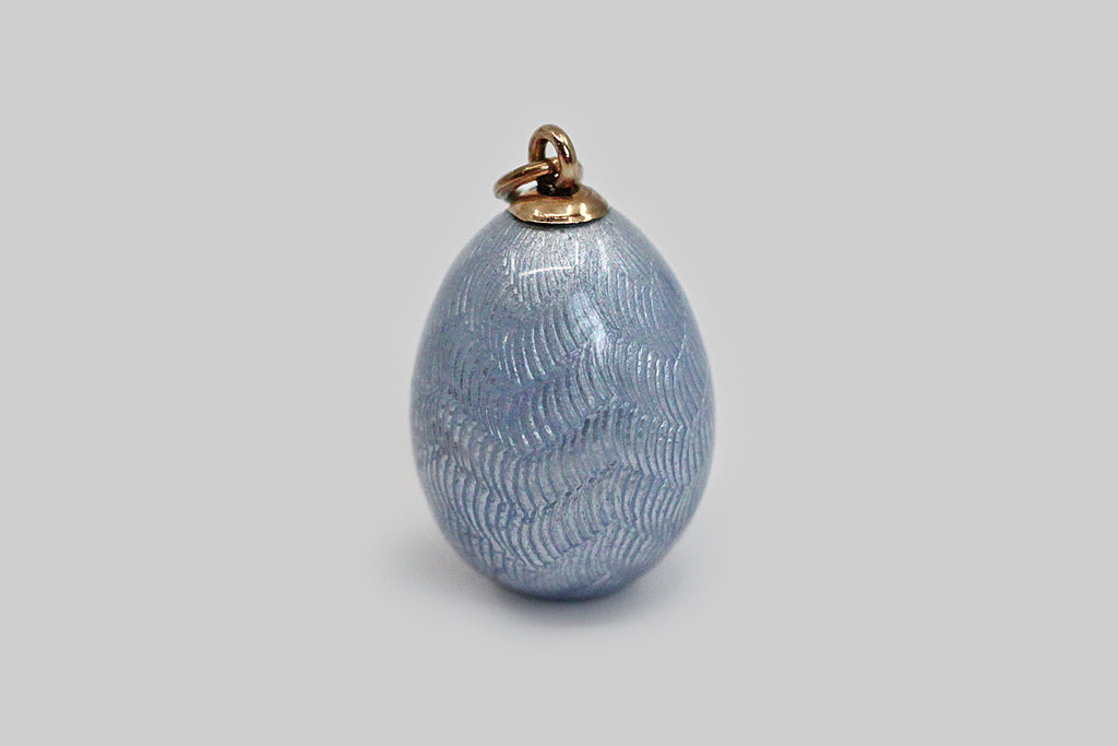 A lovely, Imperial Russian miniature egg pendant, made around the turn of the 20th century. This egg-shaped pendant is modeled in 56 zolotnik gold, and is decorated with fine, powder-blue guilloche enamel work, whose pattern resembles layered feathers or leaves. This little egg has a small six-pointed star on its bottom. We are confident that this egg belongs to the house of Fabergé
