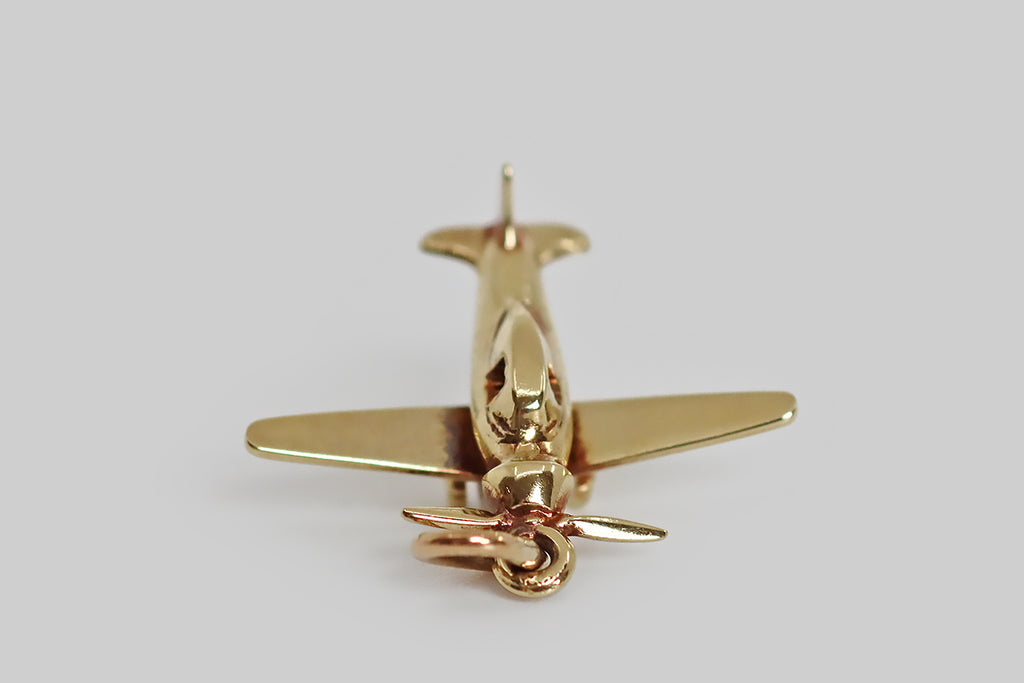 Poor Mouchette | Curated Antique Jewelry, Vintage Jewelry & Engagement Rings | Portland, Oregon | An adorable 1930s charm, modeled as a single engine airplane, in 14k yellow gold, by the Newark jewelers Sloan & Co. This lovely miniature plane is highly detailed, with small, open widows, little wheels, and a piston style nose. We think it's a nice reminder of times long ago, when we used to travel to distant lands