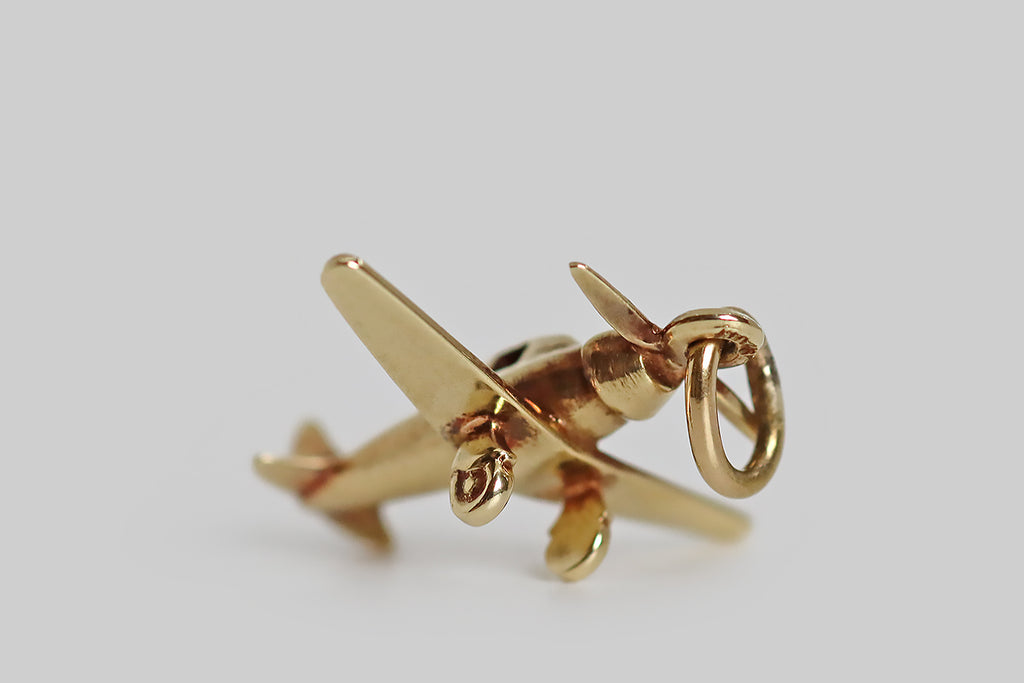 Poor Mouchette | Curated Antique Jewelry, Vintage Jewelry & Engagement Rings | Portland, Oregon | An adorable 1930s charm, modeled as a single engine airplane, in 14k yellow gold, by the Newark jewelers Sloan & Co. This lovely miniature plane is highly detailed, with small, open widows, little wheels, and a piston style nose. We think it's a nice reminder of times long ago, when we used to travel to distant lands