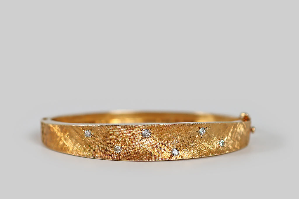Antique Jewelry Portland, Vintage Jewelry Portland , Antique Engagement Rings | Poor Mouchette | A very cool mid 20th century bangle bracelet (oval), modeled in 14k yellow gold, whose smooth, tapering form is subtly anticlastic. This bangle is beautifully finished with fine, cross-hatched, Florentine engraving. Six small diamonds are scattered across its sparkling face, where they rest in star-shaped seats. This bracelet is also embellished with pierced details 