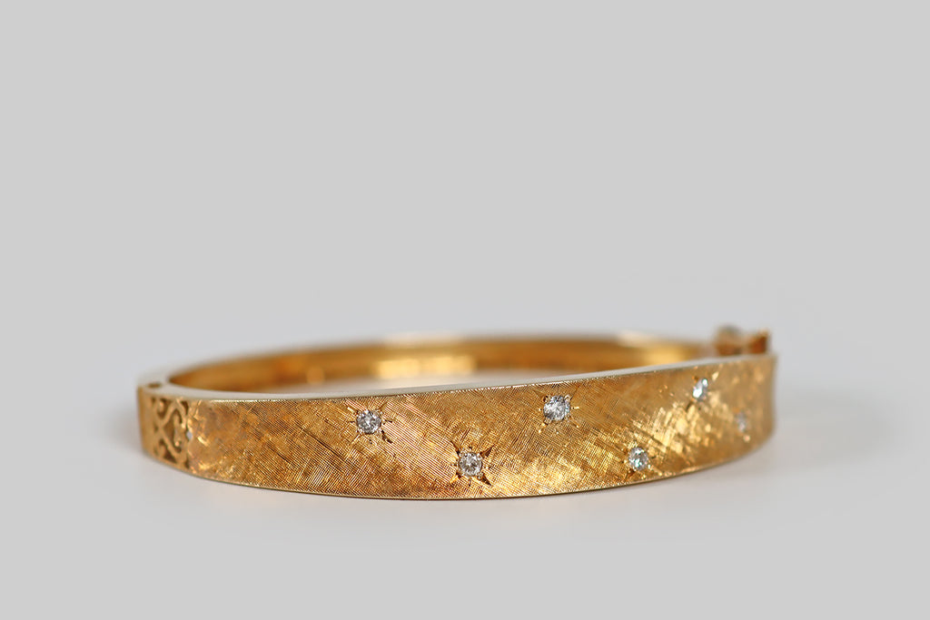 Antique Jewelry Portland, Vintage Jewelry Portland , Antique Engagement Rings | Poor Mouchette | A very cool mid 20th century bangle bracelet (oval), modeled in 14k yellow gold, whose smooth, tapering form is subtly anticlastic. This bangle is beautifully finished with fine, cross-hatched, Florentine engraving. Six small diamonds are scattered across its sparkling face, where they rest in star-shaped seats. This bracelet is also embellished with pierced details