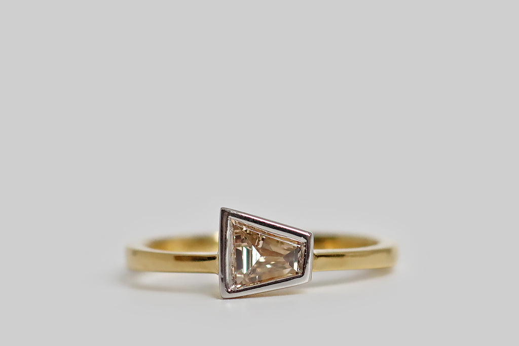Poor Mouchette | Curated Antique Jewelry, Vintage Jewelry & Engagement Rings | Portland, Oregon | A unique, low-profile engagement ring, modeled in 18k yellow gold and platinum, whose gem is a vintage, fancy-colored, tapered baguette diamond (light brown, VS, .41 carats). Our sparkling, pinkish-brown, trapezoidal diamond is set in a smooth, boxy, platinum bezel— it rests at the center of the ring's square, tapering shank. This minimalist ring is substantially made, with clean, crisp lines. 