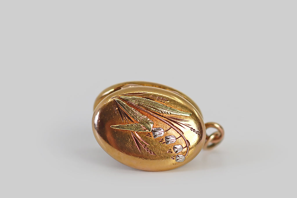Antique Jewelry Portland, Vintage Jewelry Portland , Antique Engagement Rings | Poor Mouchette | A diminutive Victorian era locket, modeled in 18k gold, whose oval face is decorated with applied lily of the valley decor. This decoration consists of four nodding platinum blossoms that hang from a rose gold stem, a pair of green gold leaves that are posted at the base of the flower, and deeply engraved springs of meadow grass that fill out the little scene.