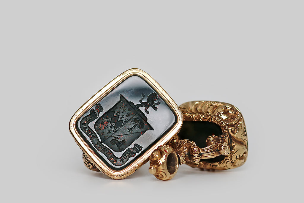 Poor Mouchette | Curated Antique Jewelry, Vintage Jewelry & Engagement Rings | Portland, Oregon | A striking, extra-large, Georgian era fob, modeled in 14k yellow gold and set with a rectangular, intaglio-carved, bloodstone gem. This finely-carved wax seal features a coat of arms, atop which stands a rampant lion. This coat of arms is "impaled" to indicate a marriage. The sinister field is divided, diagonally, "party per bend—" the charge depicted in the top half of this field is an eradicated tree