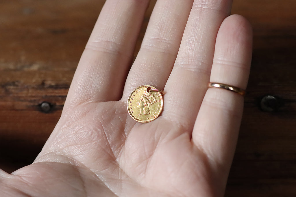 An original 1852 (civil war era) type-3 Liberty Dollar (90% gold, or approx 22k) designed by the American portraitist and engraver James B Longacre, holed and fitted with a 14k gold jump ring so it can be worn as a pendant or charm. This little coin features a left facing bust of liberty