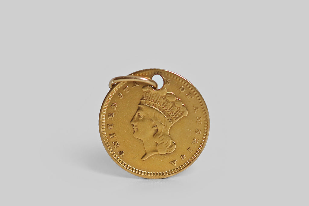 An original 1852 (civil war era) type-3 Liberty Dollar (90% gold, or approx 22k) designed by the American portraitist and engraver James B Longacre, holed and fitted with a 14k gold jump ring so it can be worn as a pendant or charm. This little coin features a left facing bust of liberty