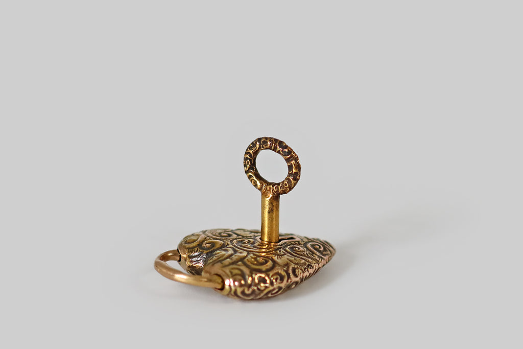 Antique Jewelry Portland, Vintage Jewelry Portland , Antique Engagement Rings | Poor Mouchette | A lovely Victorian-era, repoussé heart padlock, modeled in 14k yellow gold, that is still partnered with its original 14k gold key! This antique charm is a functioning lock, and it is in wonderful condition. The heart-shaped lock is decorated all-over with flowers and fine, swirling, baroque forms, and the key's top echos this motif.