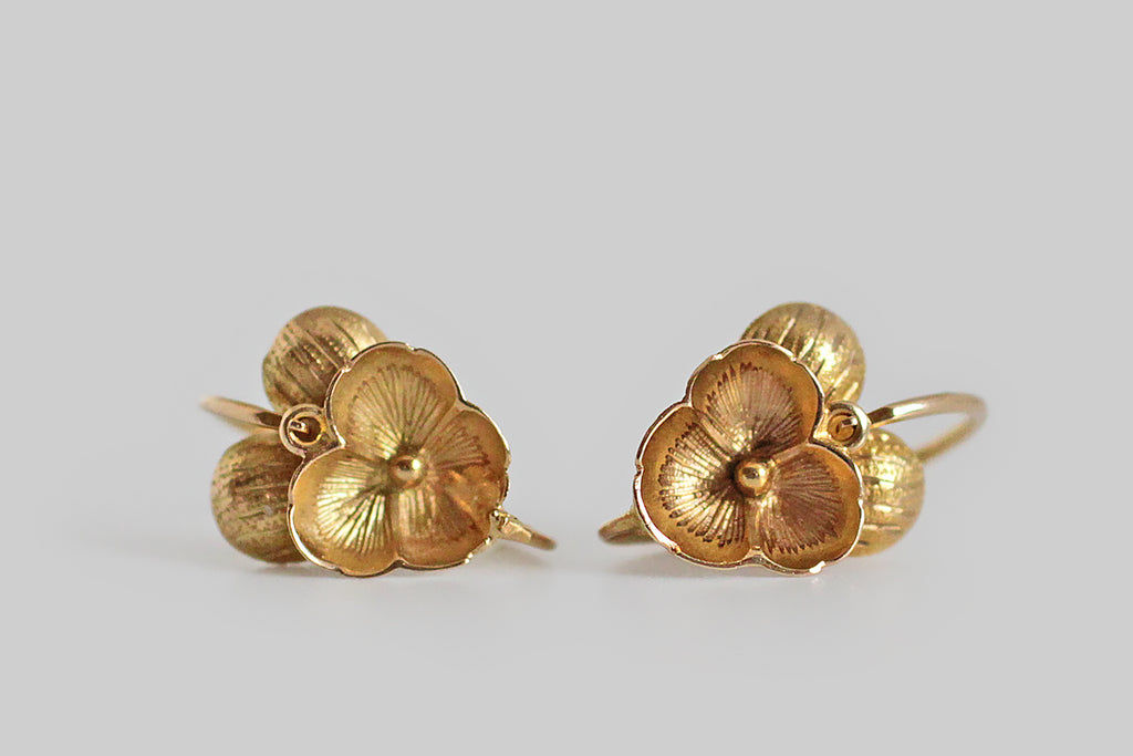 A darling pair of Victorian-era, back-to-front threading dormeuse pansy earrings, made in 18k yellow gold. These miniature flowers are quite realistic, with concave and convex forms, as well as engraved and textural details, that give them striking dimensionality. 