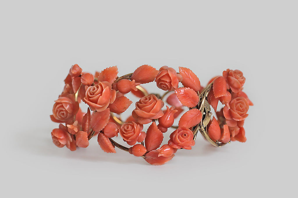 Poor Mouchette | Curated Antique Jewelry, Vintage Jewelry & Engagement Rings | Portland, Oregon | A romantic, Victorian era, hinged cuff bracelet, modeled in 14k yellow gold, that takes the form of a briary, trellised arrangment of roses. The bracelet's plump roses, rosebuds, and serrate leaves are each masterfully hand-carved from natural, salmon-colored coral. They are individually mounted atop a substantial, wirework frame