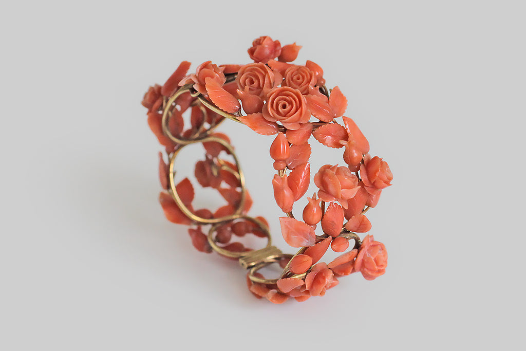 Poor Mouchette | Curated Antique Jewelry, Vintage Jewelry & Engagement Rings | Portland, Oregon | A romantic, Victorian era, hinged cuff bracelet, modeled in 14k yellow gold, that takes the form of a briary, trellised arrangment of roses. The bracelet's plump roses, rosebuds, and serrate leaves are each masterfully hand-carved from natural, salmon-colored coral. They are individually mounted atop a substantial, wirework frame