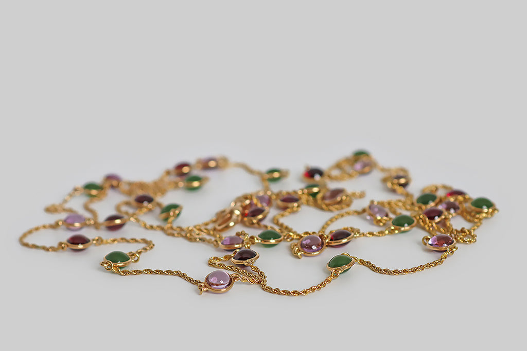 Poor Mouchette | Curated Antique Jewelry, Vintage Jewelry & Engagement Rings | Portland, Oregon | A striking, Victorian era, long guard station chain, modeled in 14k yellow gold, whose lengths of slender, twisted rope are punctuated with bezel-set, gemstone spacers. These amethyst, garnet, and nephrite jade cabochons are domed on both sides— they are mounted in slim, “floating” bezels, so they are never upside down. This antique chain is fitted with a 14k gold dog clip