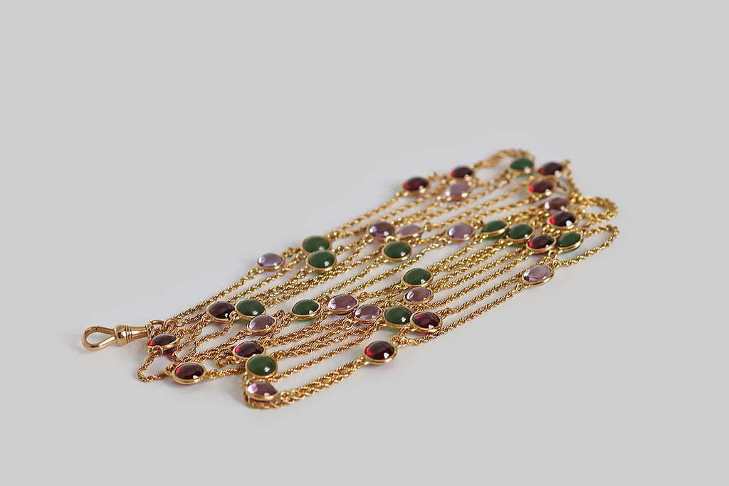 Poor Mouchette | Curated Antique Jewelry, Vintage Jewelry & Engagement Rings | Portland, Oregon | A striking, Victorian era, long guard station chain, modeled in 14k yellow gold, whose lengths of slender, twisted rope are punctuated with bezel-set, gemstone spacers. These amethyst, garnet, and nephrite jade cabochons are domed on both sides— they are mounted in slim, “floating” bezels, so they are never upside down. This antique chain is fitted with a 14k gold dog clip
