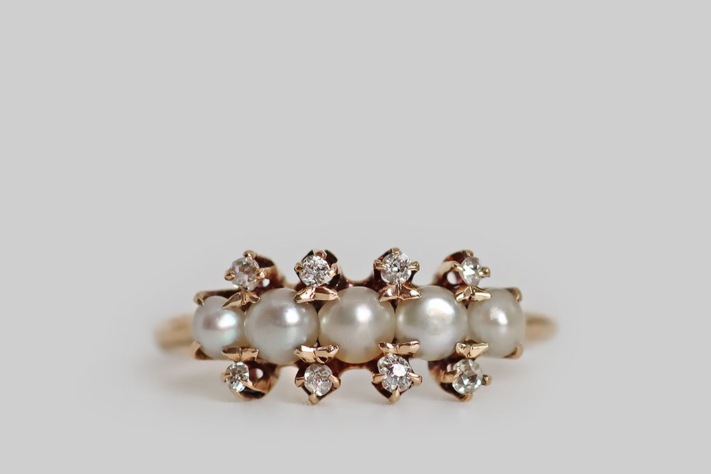 Poor Mouchette | Curated Antique Jewelry, Vintage Jewelry & Engagement Rings | Portland, Oregon | A delicate, Victorian-era cluster ring, modeled in 14k rosy-yellow gold, whose five primary gems are a series of luminous, white half-pearls. These pearls are set horizontally, across the curved ring face, in shared claw-like prongs. They are subtly graduated, with the largest pearl resting at center. Eight, small, old mine cut diamonds further decorate the ring face