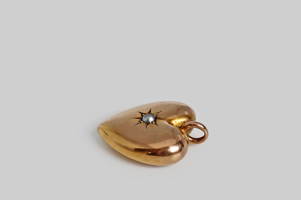 Poor Mouchette | Curated Antique Jewelry, Vintage Jewelry & Engagement Rings | Portland, Oregon | A charming, Victorian era heart pendant, modeled in 9k rosy yellow gold. This classic puffed heart is beautifully and substantially made— it has a lovely form, with smooth edges, and thick-walled construction. An expressively-carved, eight-pointed star rests at the center of this heart, where it holds a silvery, semi-baroque seed pearl. This is a wonderful, easy-to-wear, everyday pendant