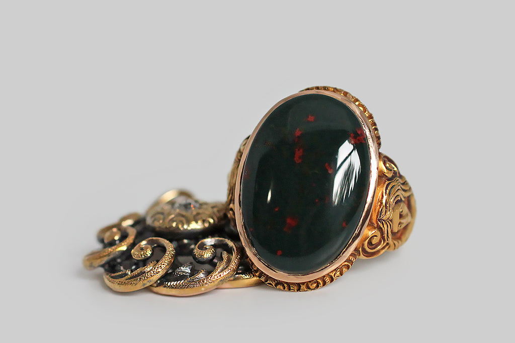 A strange and wonderful Victorian-era ring, modeled in bloomed 14k yellow gold, whose shoulders are occupied by a pair of dryads. These finely-carved maidens have long, flowing hair . . . their bare chests transition into a tree-like body, below which sprigs of plant life grow. The curling figures that decorate the ring's shoulders suggest the dryads' up-stretched arms, transforming into limbs. We think this unusual decor probably references the myth of Daphne 