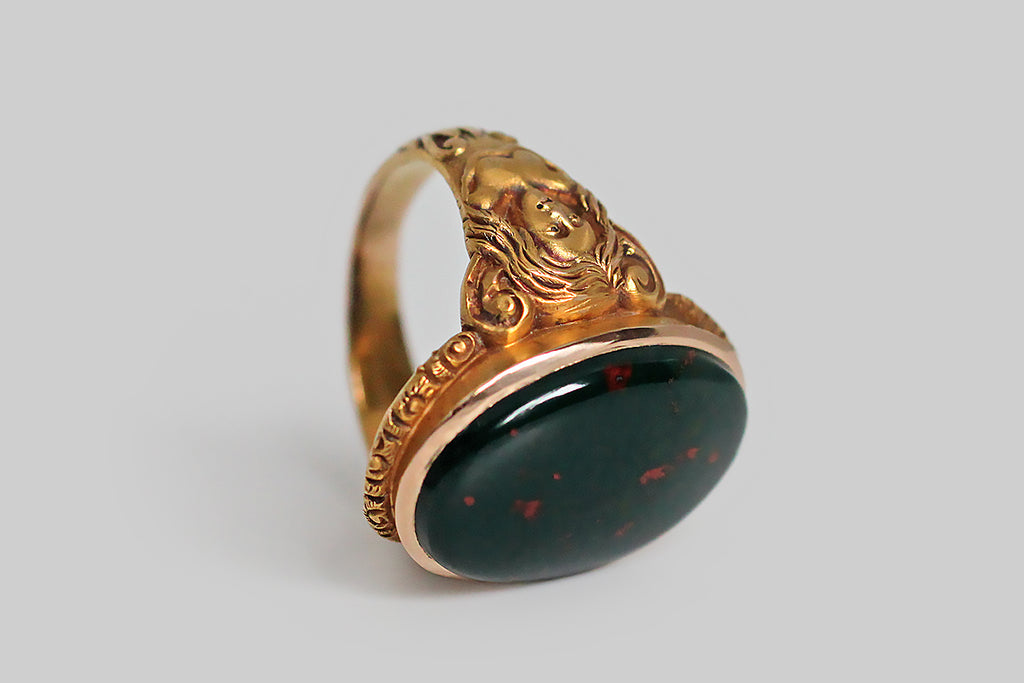 A strange and wonderful Victorian-era ring, modeled in bloomed 14k yellow gold, whose shoulders are occupied by a pair of dryads. These finely-carved maidens have long, flowing hair . . . their bare chests transition into a tree-like body, below which sprigs of plant life grow. The curling figures that decorate the ring's shoulders suggest the dryads' up-stretched arms, transforming into limbs. We think this unusual decor probably references the myth of Daphne 