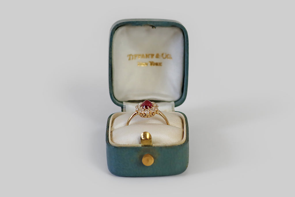  Antique Jewelry Portland, Vintage Jewelry Portland , Antique Engagement Rings | Poor Mouchette | A beautiful, antique, Tiffany & Co. ring, modeled in 18k yellow gold, whose primary gem is a natural, untreated, .93 carat sugarloaf ruby cabochon (AGL certified) encircled by a halo of ten chunky, old European cut diamonds. This oval, 'pigeon's blood' ruby cabochon is transparent and deeply-saturated