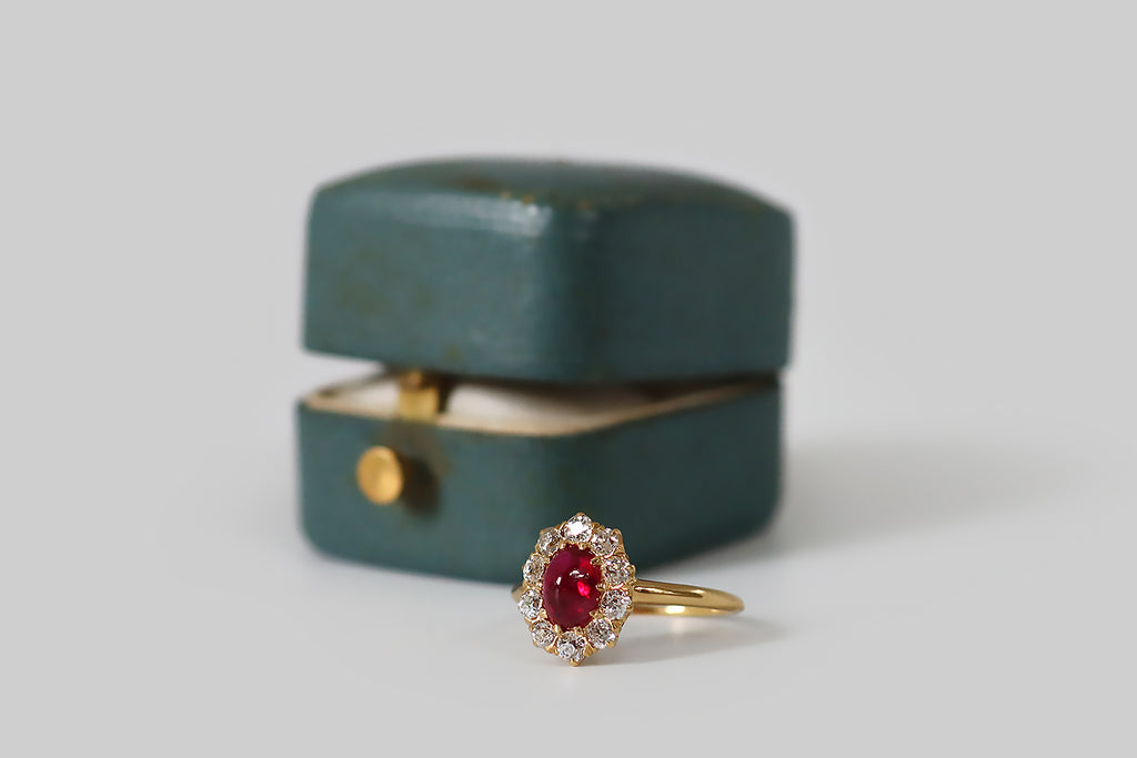 Antique Jewelry Portland, Vintage Jewelry Portland , Antique Engagement Rings | Poor Mouchette | A beautiful, antique, Tiffany & Co. ring, modeled in 18k yellow gold, whose primary gem is a natural, untreated, .93 carat sugarloaf ruby cabochon (AGL certified) encircled by a halo of ten chunky, old European cut diamonds. This oval, 'pigeon's blood' ruby cabochon is transparent and deeply-saturated