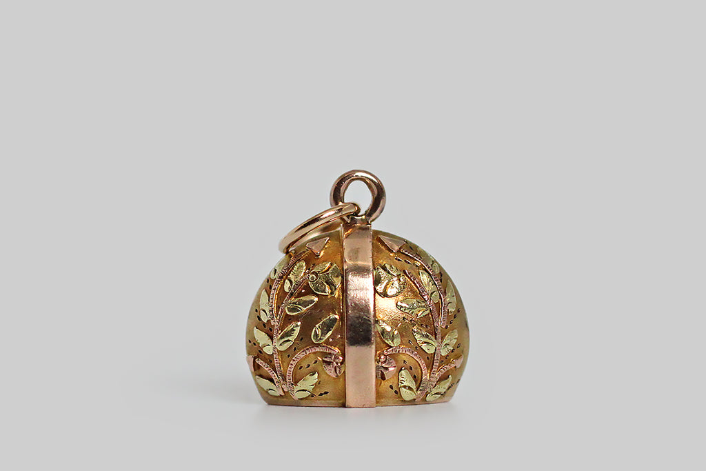 A sweet, miniature, Victorian era fob, modeled in yellow, rose, and green 10k gold. This weight-shaped charm is decorated with masterfully hand-sawed leaves and flowers. The tiny plant forms were applied, piece by piece, to the surface of the charm— they bend gracefully, and have a somewhat fantastical appearance, with their circular, nodding blooms and arrow-shaped seed heads. 