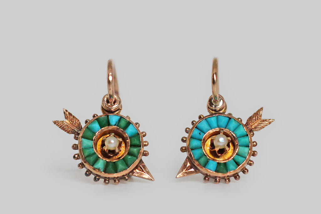 Poor Mouchette | Curated Antique Jewelry, Vintage Jewelry & Engagement Rings | Portland, Oregon | A dainty pair of Victorian-era drop earrings, modeled as miniature archery targets (with tiny piercing arrows) in 14k rosy yellow gold. These round targets are set with a series of calibre cut turquoise gems (30), which fit perfectly together and range in color from sky blue to dark green. Their outside edges are decorated with small beads of granulation