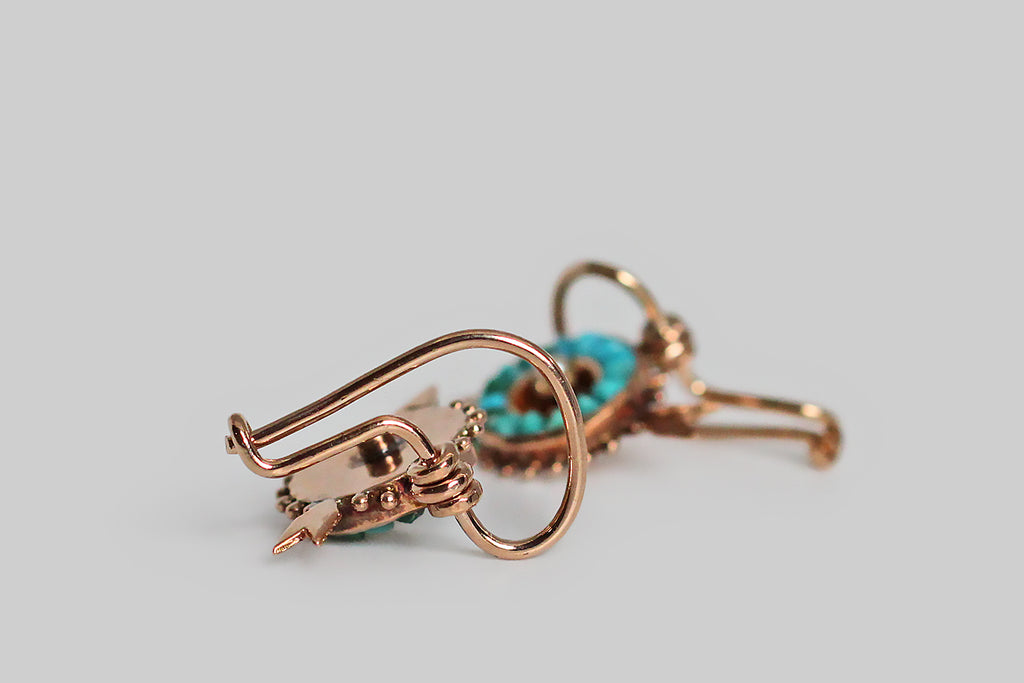 Poor Mouchette | Curated Antique Jewelry, Vintage Jewelry & Engagement Rings | Portland, Oregon | A dainty pair of Victorian-era drop earrings, modeled as miniature archery targets (with tiny piercing arrows) in 14k rosy yellow gold. These round targets are set with a series of calibre cut turquoise gems (30), which fit perfectly together and range in color from sky blue to dark green. Their outside edges are decorated with small beads of granulation