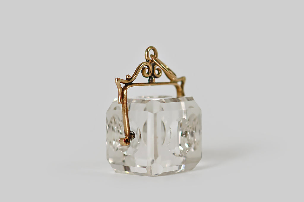 Antique Jewelry Portland, Vintage Jewelry Portland , Antique Engagement Rings | Poor Mouchette | An unusual Victorian era pendant fob, modeled in 14k yellow gold, whose focal element is an optically-clear, hand-carved, rock crystal cube. This crystal cube has beveled sides, clipped corners, and each of its faces is decorated with a single recessed circle. When viewed face-on, these circles create an interesting optical illusion, that reads like a hall of mirrors.