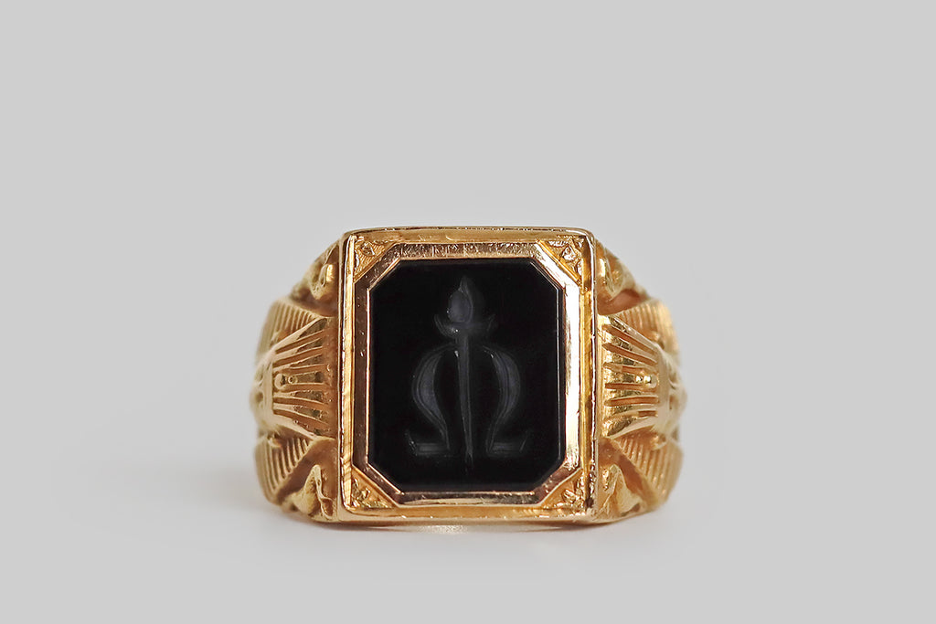 Poor Mouchette | Curated Antique Jewelry, Vintage Jewelry & Engagement Rings | Portland, Oregon | An exceptional Art Deco era intaglio signet ring, modeled in 14k yellow gold, whose onyx seal is carved with a torch that intersects the greek letter omega (the end). This seal is held in an elaborate mount, whose finely-carved, figural decor has an Egyptian flavor⁠— the ring's broad shoulders both feature the bust of the pharaoh Hatshepsut