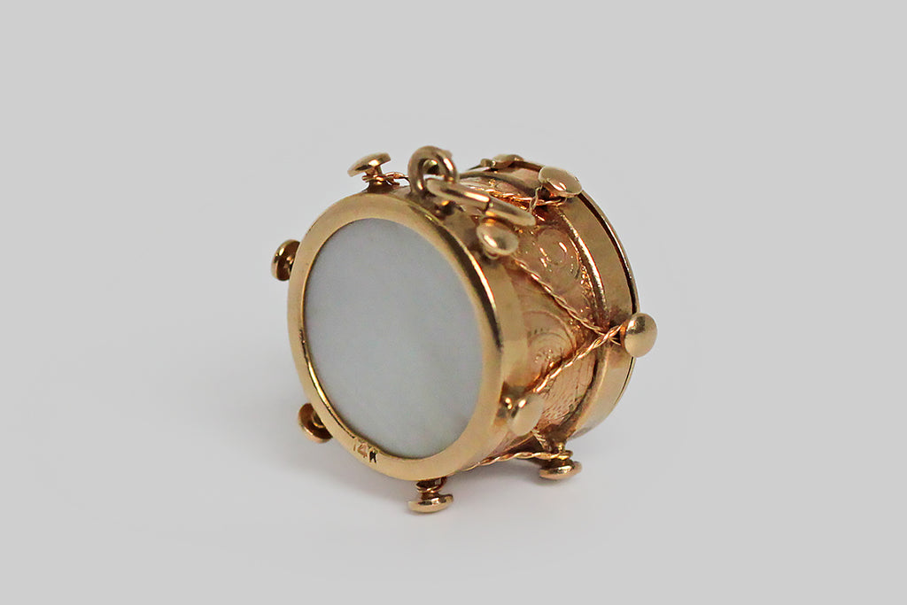 An unusual WW1 (Edwardian) era watch fob, modeled as a highly realistic rope-and-tension snare drum. This 14k gold drum has a lightly-domed glass front that opens to reveal a compartment, made to hold a miniature, folded, 48-star American flag. The reverse drum face is a set with an iridescent mother of pearl disc. 